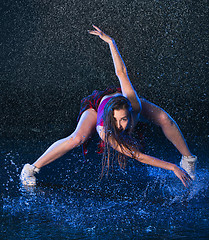 Image showing The young beautiful modern dancer dancing under water drops