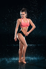 Image showing Young tanned fit woman with beautiful sporty buttocks and slim with water drops