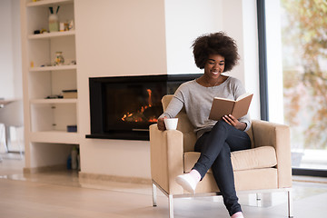 Image showing black woman reading book  in front of fireplace