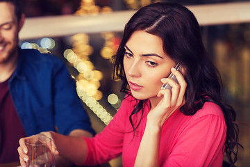 Image showing woman with smartphone and friends at restaurant