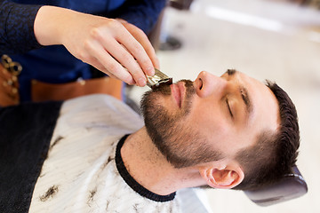 Image showing man and barber with trimmer cutting beard at salon