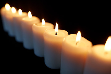 Image showing candles burning in darkness over black background