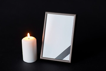 Image showing black ribbon on photo frame and candle at funeral