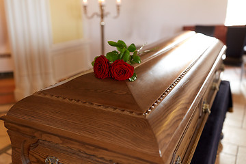 Image showing red rose flowers on wooden coffin in church