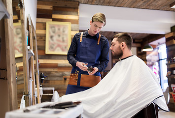 Image showing barber showing hair styling wax to male customer