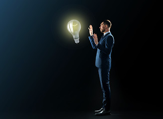 Image showing businessman with lightbulb over black background