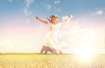 Image showing happy woman in wreath jumping on cereal field