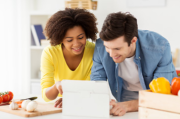 Image showing happy couple with tablet pc cooking food at home