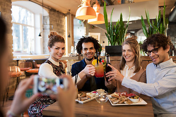 Image showing happy friends clinking drinks at bar or cafe