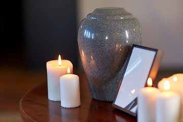 Image showing photo frame, cremation urn and candles on table