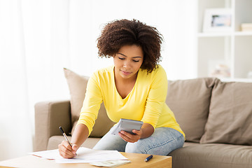 Image showing african woman with papers and calculator at home