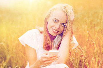 Image showing happy young woman with smartphone on cereal field