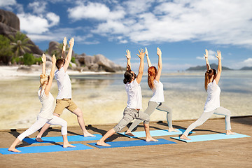 Image showing group of people making yoga exercises on beach