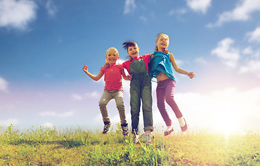 Image showing group of happy kids jumping high on green field