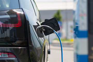 Image showing Power supply plugged into an electric car being charged.