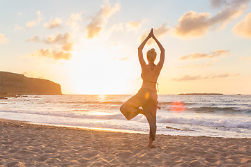 Image showing Woman practicing yoga on sea beach at sunset.