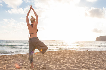 Image showing Woman practicing yoga on sea beach at sunset.