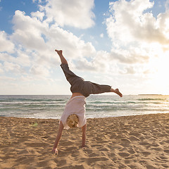 Image showing Free Happy Woman Turning Cartwheel Enjoying Sunset on Sandy Beach.