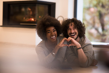 Image showing multiethnic couple showing a heart with their hands on the floor