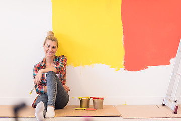 Image showing young female painter sitting on floor