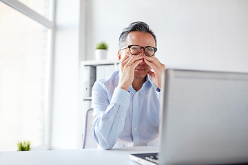 Image showing tired businessman in glasses with laptop at office