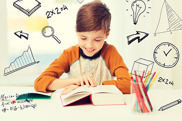 Image showing smiling, student boy reading book at home