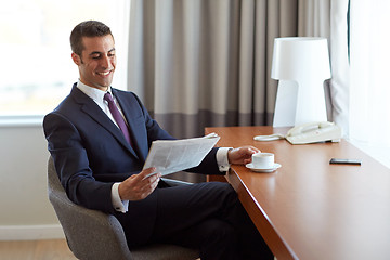 Image showing businessman reading newspaper and drinking coffee