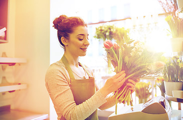 Image showing smiling florist woman making bunch at flower shop