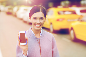 Image showing smiling woman showing smartphone over taxi in city