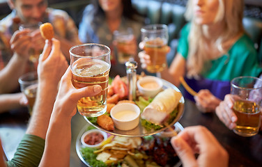 Image showing happy friends eating and drinking at bar or pub