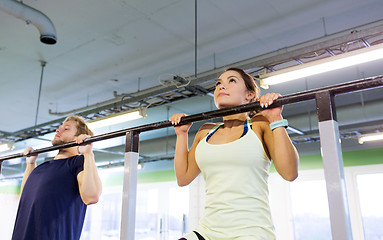 Image showing couple doing pull-ups at horizontal bar in gym