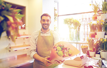 Image showing smiling florist man making bunch at flower shop