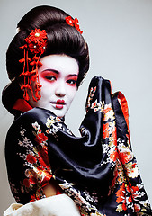 Image showing young pretty geisha in kimono with sakura and red decoration design on white background