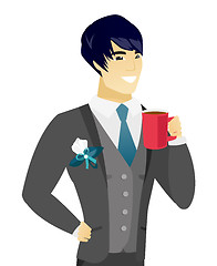 Image showing Young asian groom holding cup of coffee.