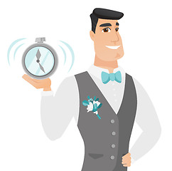 Image showing Young caucasian groom holding alarm clock.