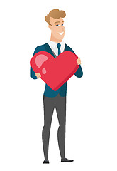 Image showing Caucasian groom holding a big red heart.