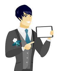 Image showing Young asian groom holding tablet computer.