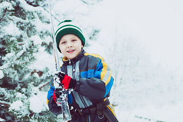 Image showing Happy little boy playing  on winter snow day.