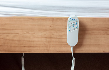 Image showing Bed remote hanging at the side from a bed