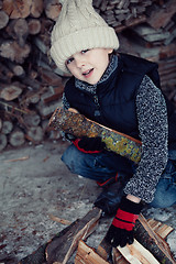 Image showing Little boy chopping firewood in the front yard at the day time.