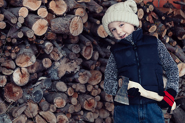 Image showing Little boy chopping firewood in the front yard at the day time.