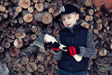 Image showing Little boy chopping firewood in the front yard at the day time.
