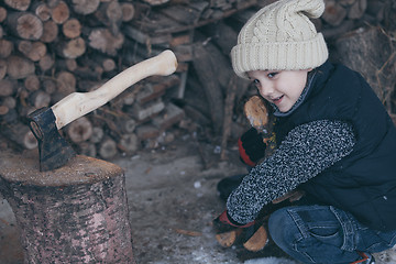 Image showing Little boy chopping firewood in the front yard at the day time.