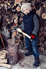 Image showing Little boy chopping firewood in the front yard at the day time.