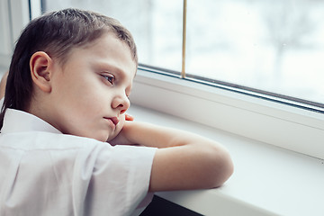 Image showing sad little boy sitting near the window