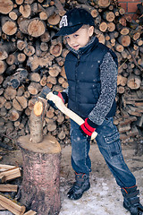 Image showing Little boy chopping firewood in the front yard at the day time.