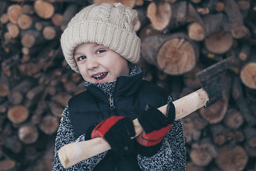 Image showing Little boy chopping firewood in the front yard at the day time.