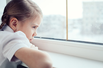 Image showing sad little girl sitting near the window