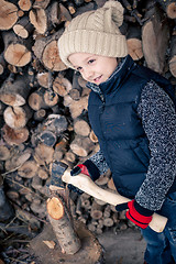 Image showing Little boy chopping firewood in the front yard at the day time.