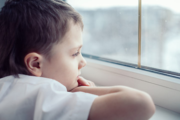 Image showing sad little boy sitting near the window